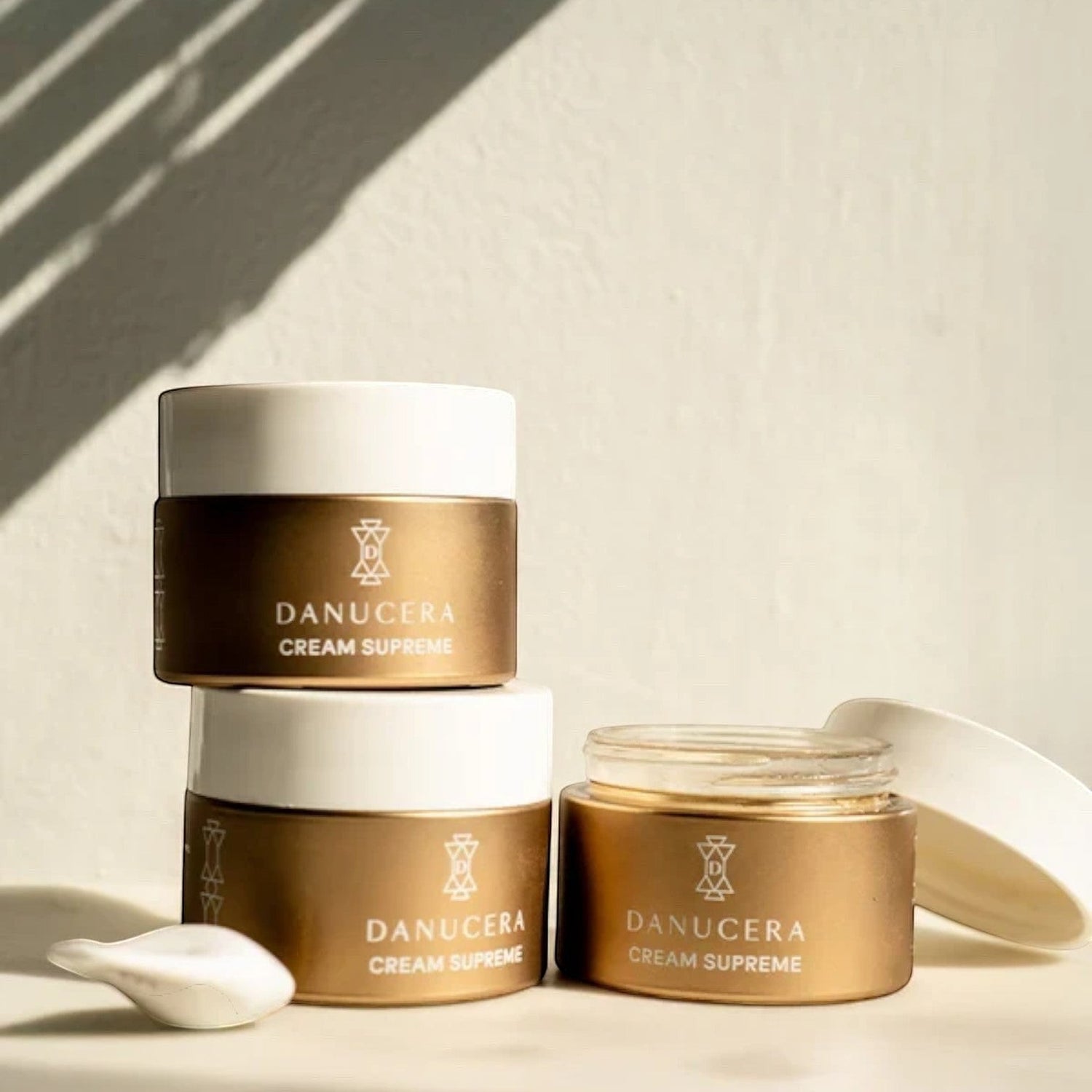 Shop Rescue Spa Danucera Cream Supreme moisturizer jars in gold and white packaging on a sunny surface.