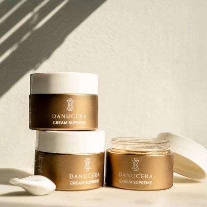 Shop Rescue Spa Danucera Cream Supreme moisturizer jars in gold and white packaging on a sunny surface.