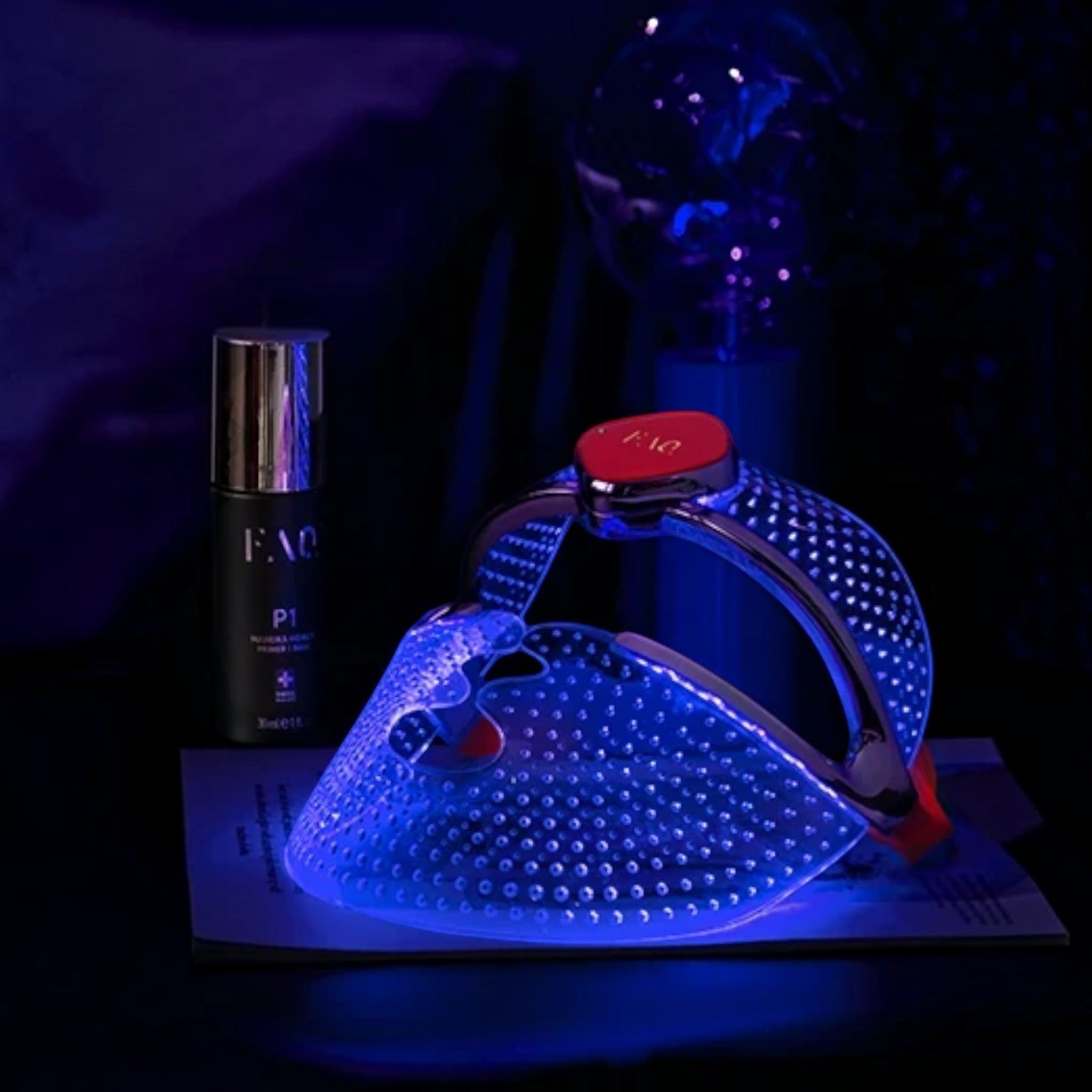 Shop Rescue Spa FAQ 201 silicone LED face mask glowing with blue light for anti-acne treatment on a dark surface