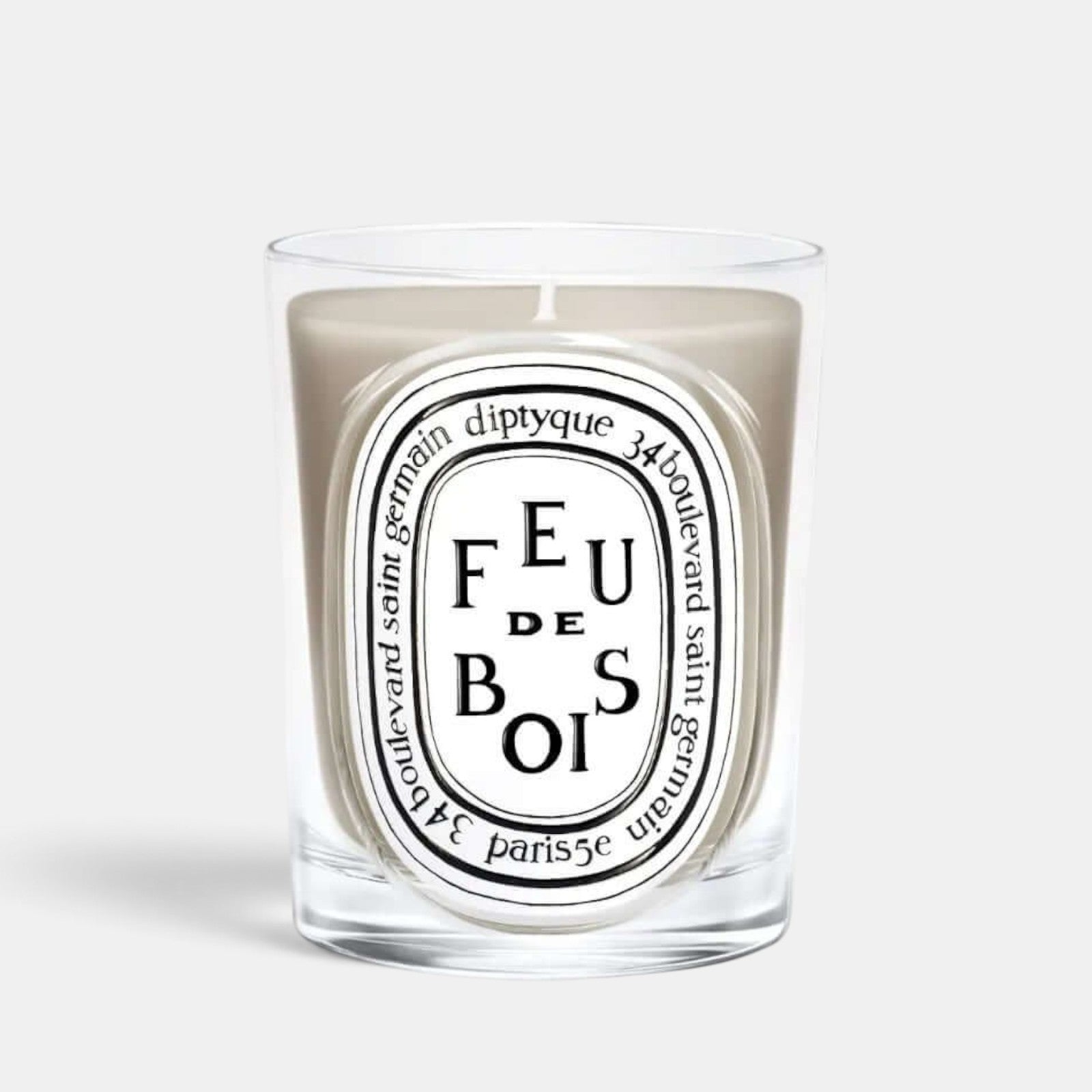 Shop Rescue Spa Diptyque Feu de Bois scented candle in a clear glass vessel with a beige wax finish