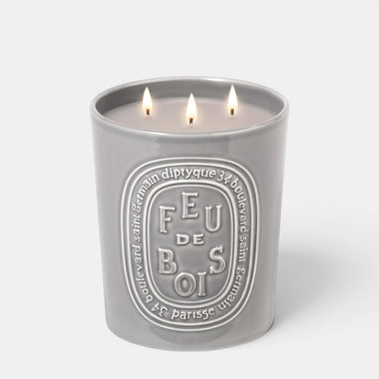Shop Rescue Spa Feu De Bois scented candle in a grey ceramic vessel with three lit wicks and embossed branding.