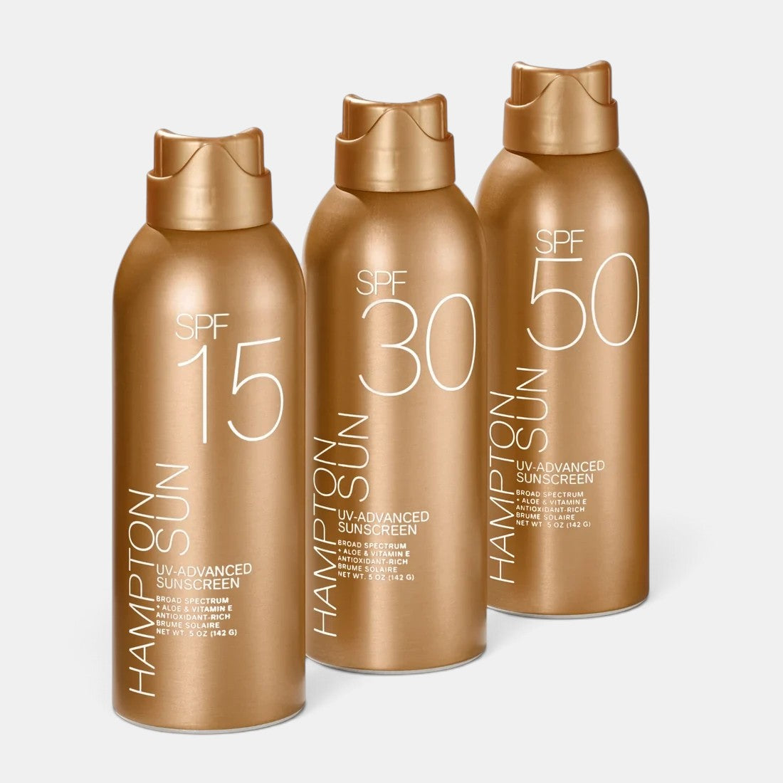 Shop Rescue Spa Hampton Sun SPF 15, 30, and 50 UV-Advanced sunscreen mist bottles in gold packaging.