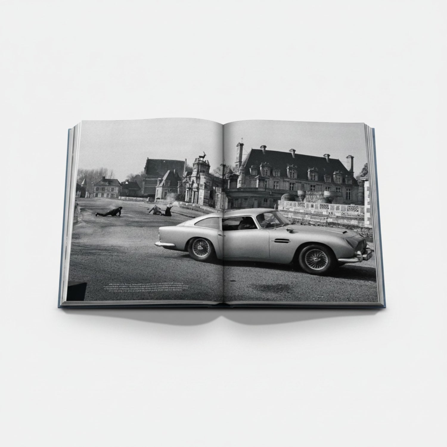 James Bond Cars book featuring an Aston Martin DB5 in a black and white scene with a chateau in the background.