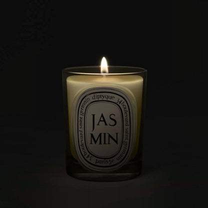 Shop Rescue Spa Jasmin scented candle in a clear glass vessel with a glowing flame against a dark background