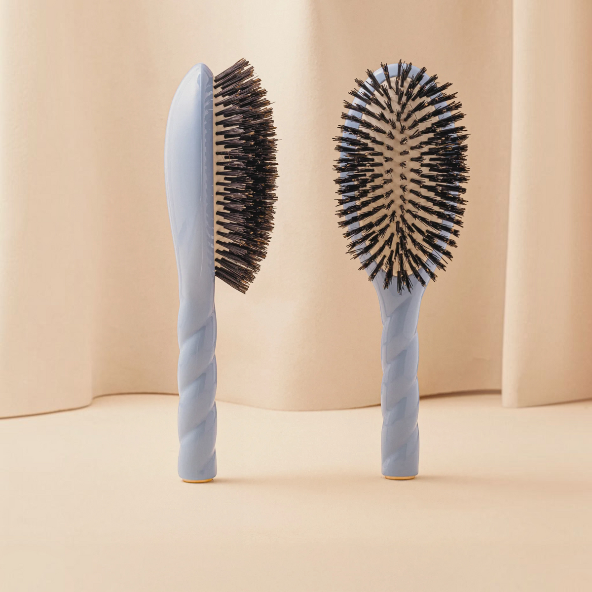 Shop Rescue Spa N.01 large boar bristle hair brush in light blue with a twisted handle design on a beige background.