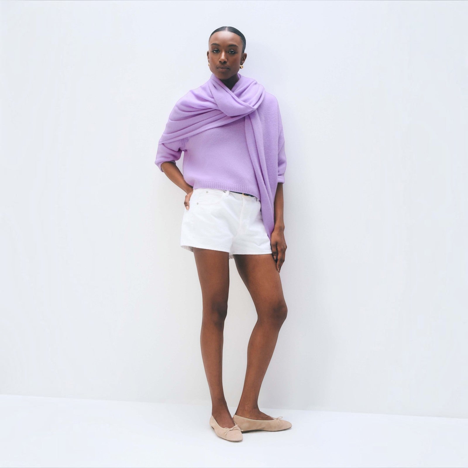 Model wearing a Shop Rescue Spa lavender fog cashmere travel wrap as a scarf over a light purple sweater and shorts.