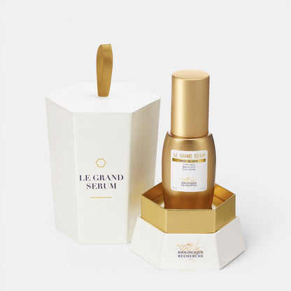 Shop Rescue Spa Le Grand Serum in a gold bottle with its white hexagonal presentation box and gold base.