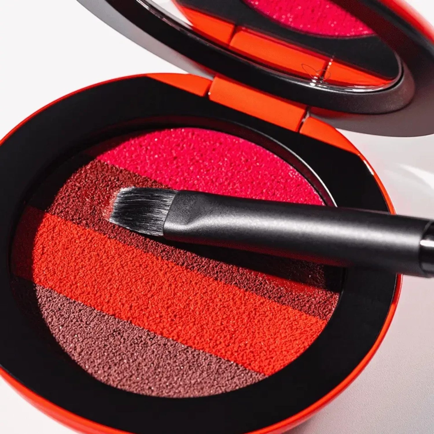 Shop Rescue Spa lip brush resting on a Westman Atelier Lip Suede palette with four shades of red and pink pigment