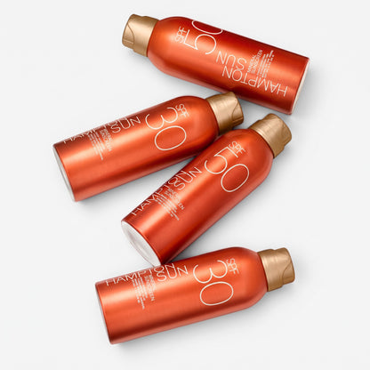 Shop Rescue Spa SPF 50 mineral sunscreen mist bottles in metallic orange packaging with gold caps on a white background