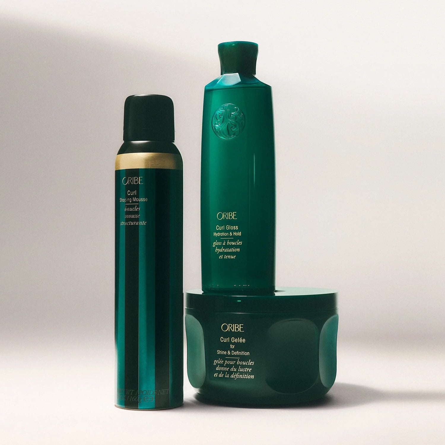 Oribe Curl Gloss Hydration &amp; Hold gel in a dark green bottle with gold accents, alongside other Oribe curl products.