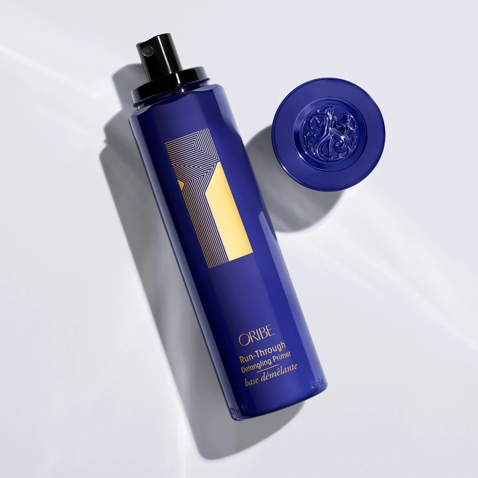 Shop Rescue Spa Oribe Run-Through Detangling Primer in a dark blue spray bottle with gold accents and a matching cap.