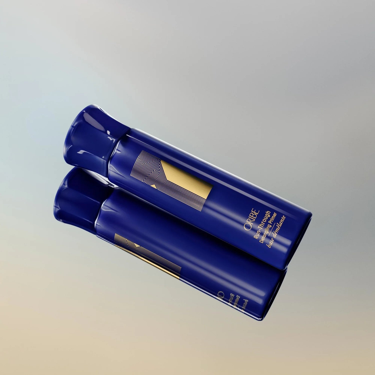 Shop Rescue Spa Oribe Run-Through Detangling Primer in a blue bottle with gold logo on a reflective surface.