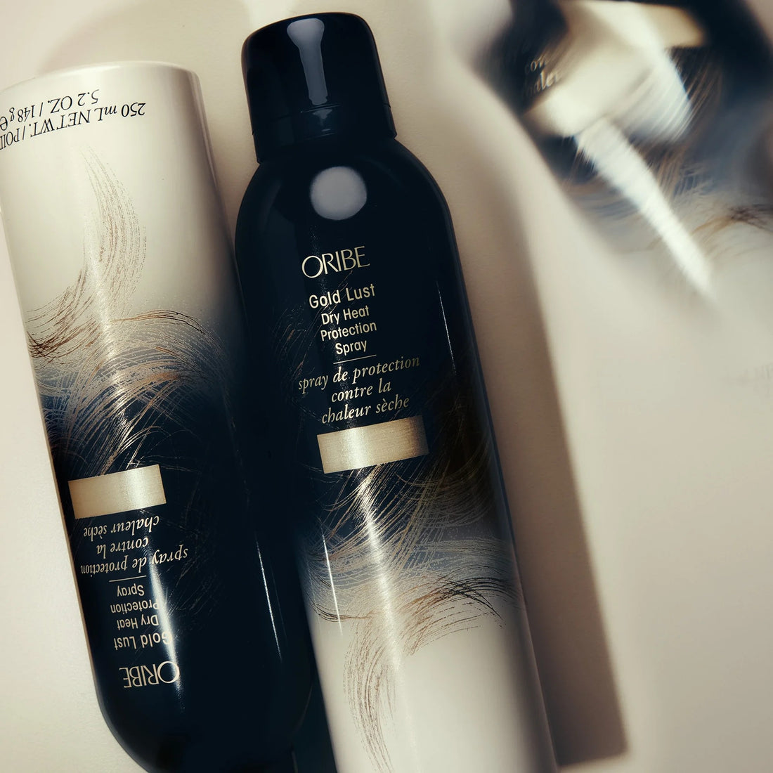 Shop Rescue Spa Oribe Gold Lust Dry Heat Protection Spray, a dark bottle with gold and white abstract design, protects hair from heat.