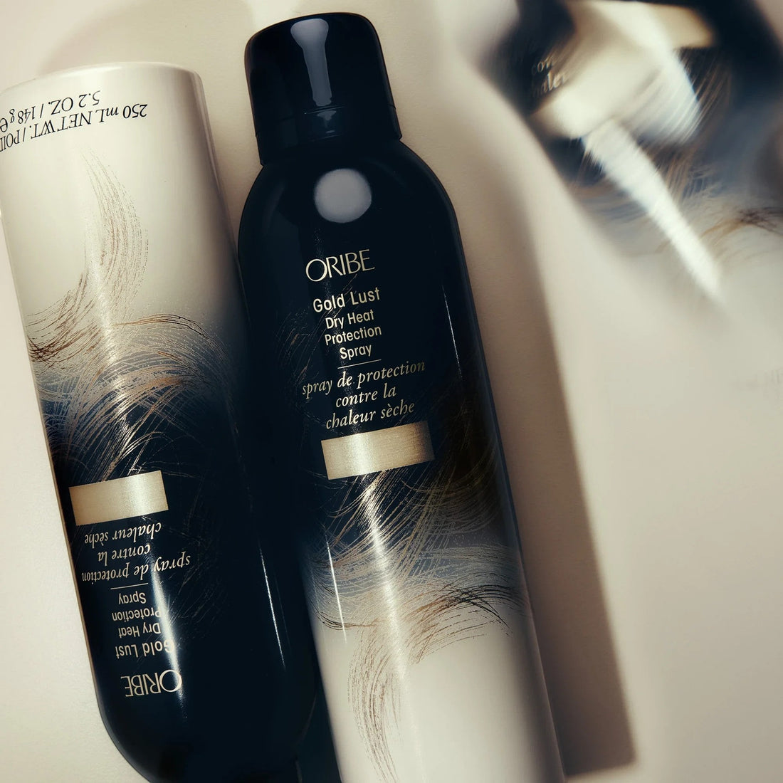 Shop Rescue Spa Oribe Gold Lust Dry Heat Protection Spray, a dark bottle with gold and white abstract design, protects hair from heat.