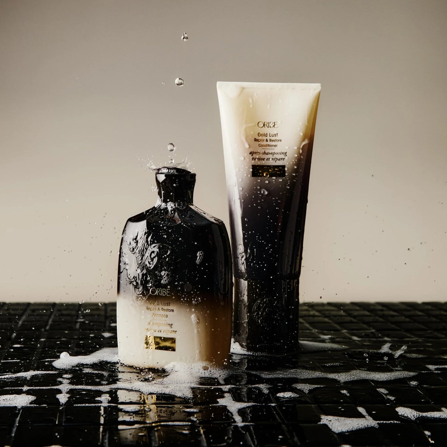 Shop Rescue Spa Oribe Gold Lust shampoo and conditioner bottles with water splashes on a black tiled surface.