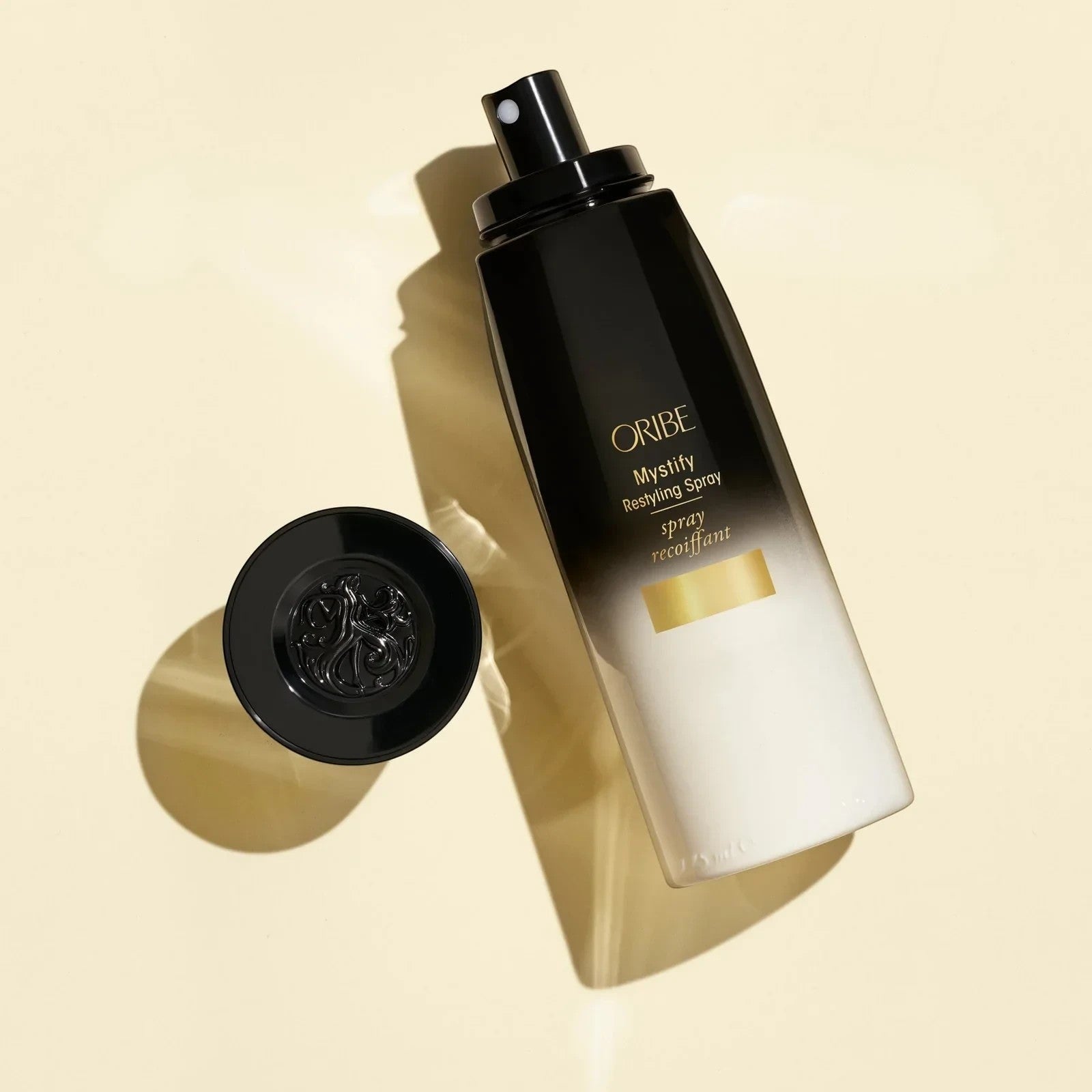 Shop Rescue Spa Oribe Mystify Restyling Spray bottle with black cap, protects hair from heat.