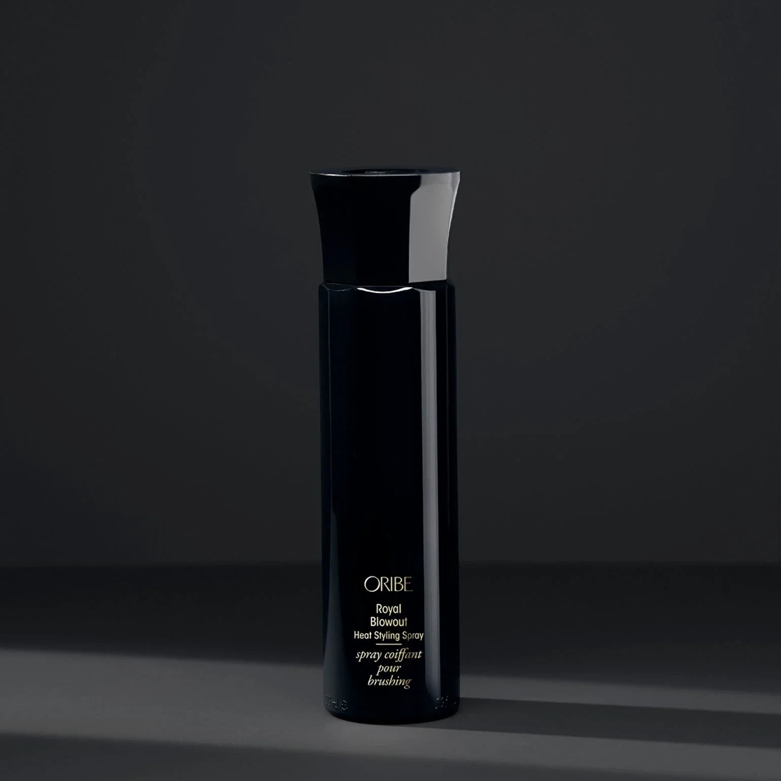 Shop Rescue Spa Oribe Royal Blowout heat styling spray in a sleek black bottle against a dark grey background.