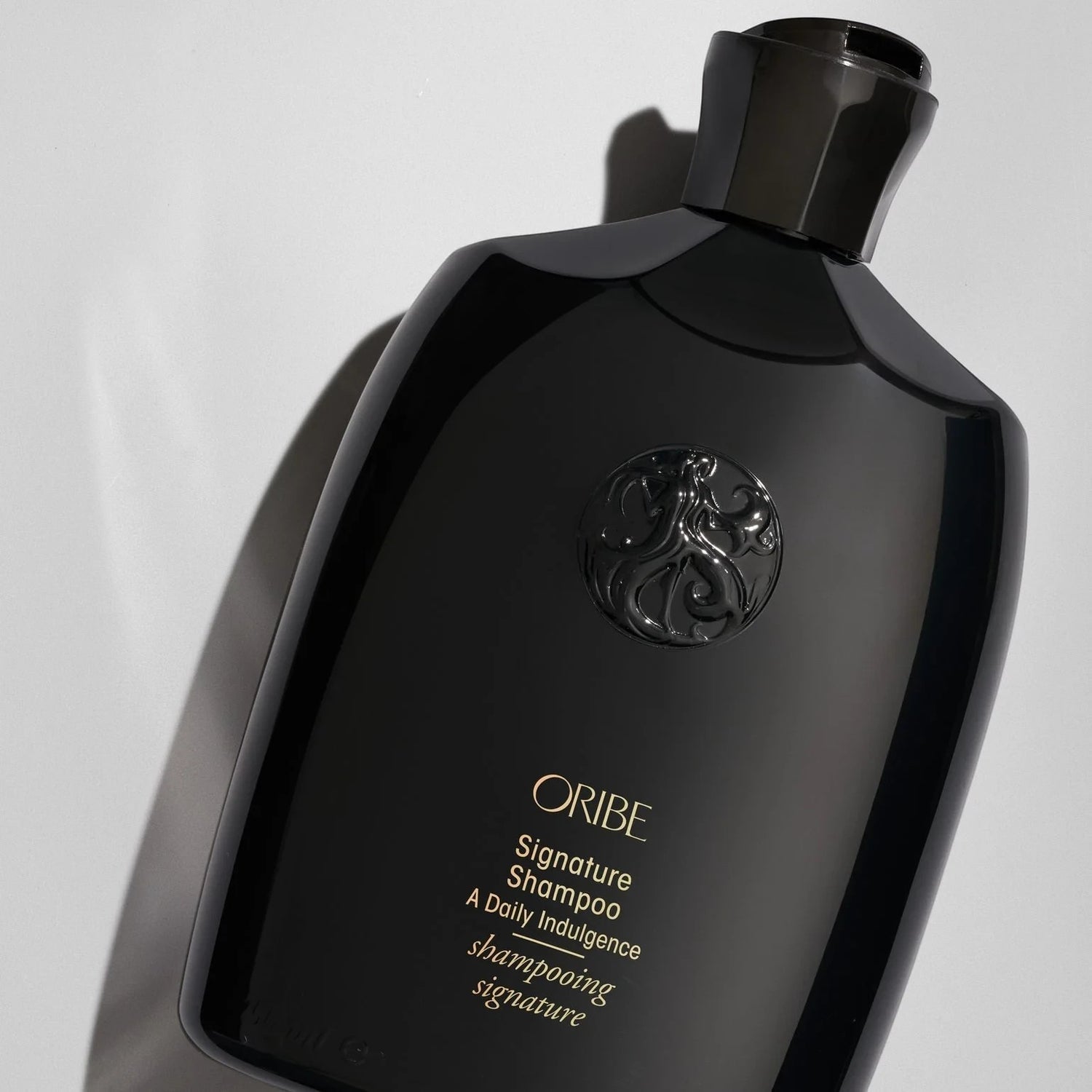 Shop Rescue Spa Oribe Signature Shampoo in a sleek black bottle with gold lettering and embossed logo detail.