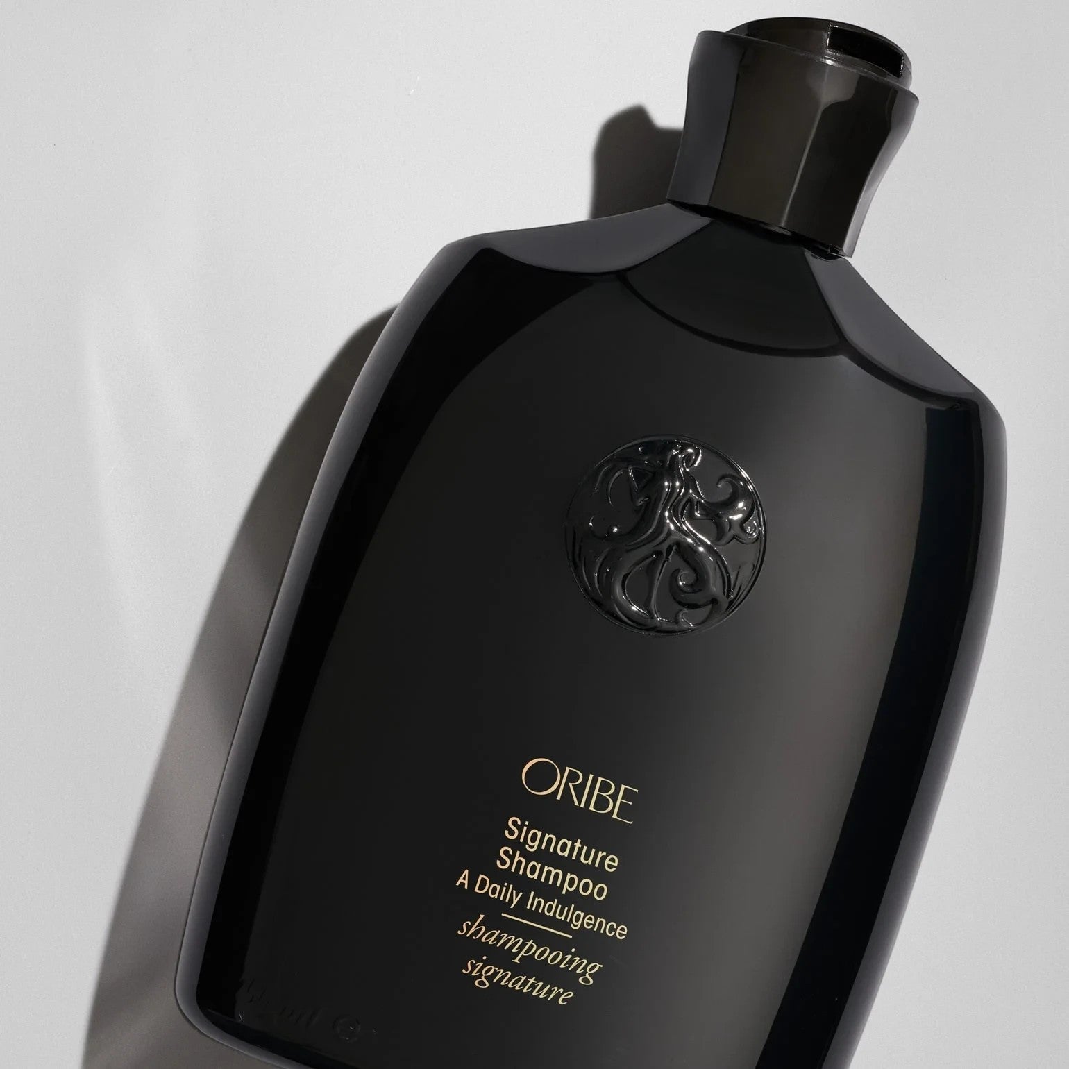 Shop Rescue Spa Oribe Signature Shampoo in a sleek black bottle with gold lettering and embossed logo detail.