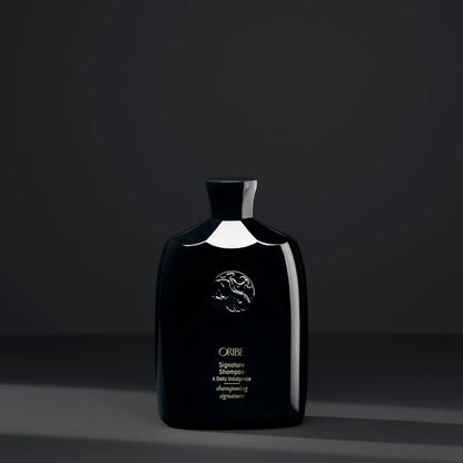 Shop Rescue Spa Oribe Signature Shampoo in a sleek black bottle with gold lettering against a dark grey background.