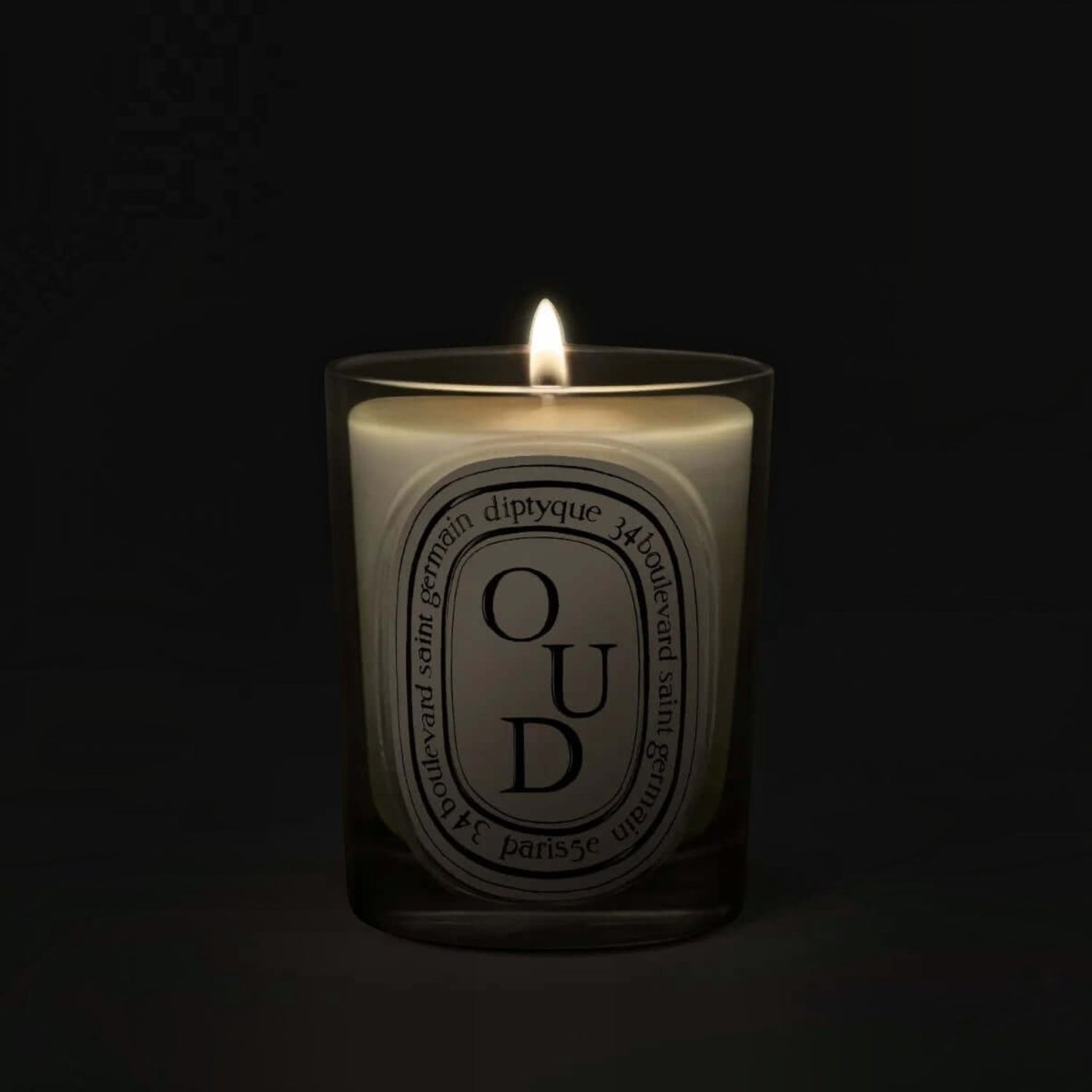 Shop Rescue Spa Oud scented candle in a glass vessel with a glowing flame against a dark background