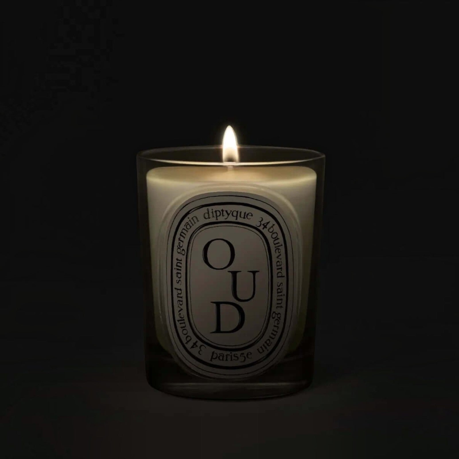 Shop Rescue Spa Oud scented candle in a glass vessel with a glowing flame against a dark background