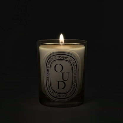 Shop Rescue Spa Oud scented candle in a glass vessel with a glowing flame against a dark background