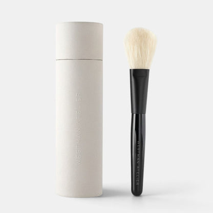 Shop Rescue Spa powder brush with soft nylon bristles and a black lacquered handle next to its protective case.