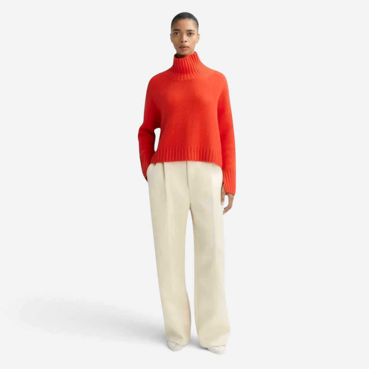 Shop Rescue Spa Girlfriend Turtleneck in bright red chunky cashmere with sleeve slits worn with cream trousers
