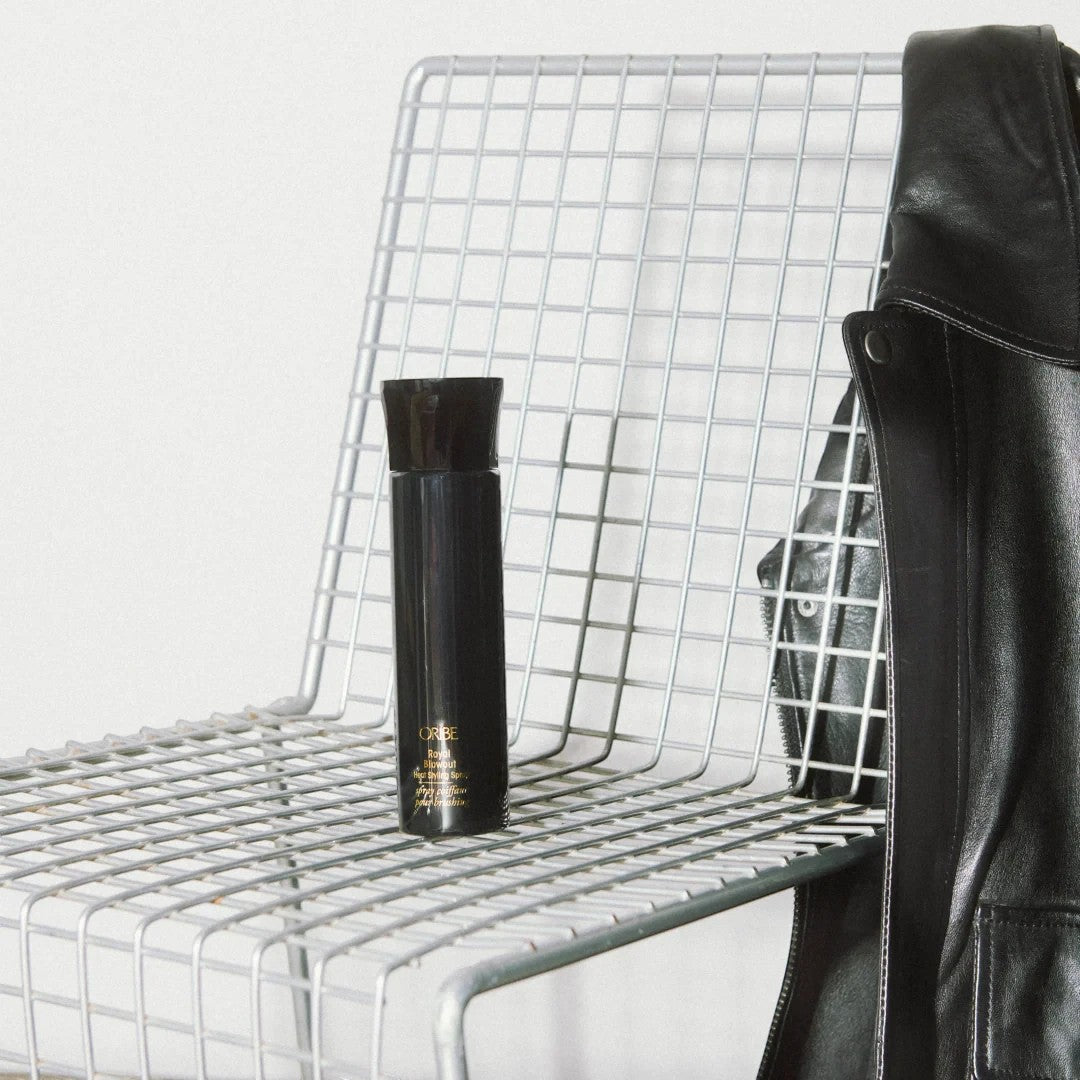 Shop Rescue Spa Royal Blowout heat styling spray bottle on a modern wire chair with a black leather jacket.