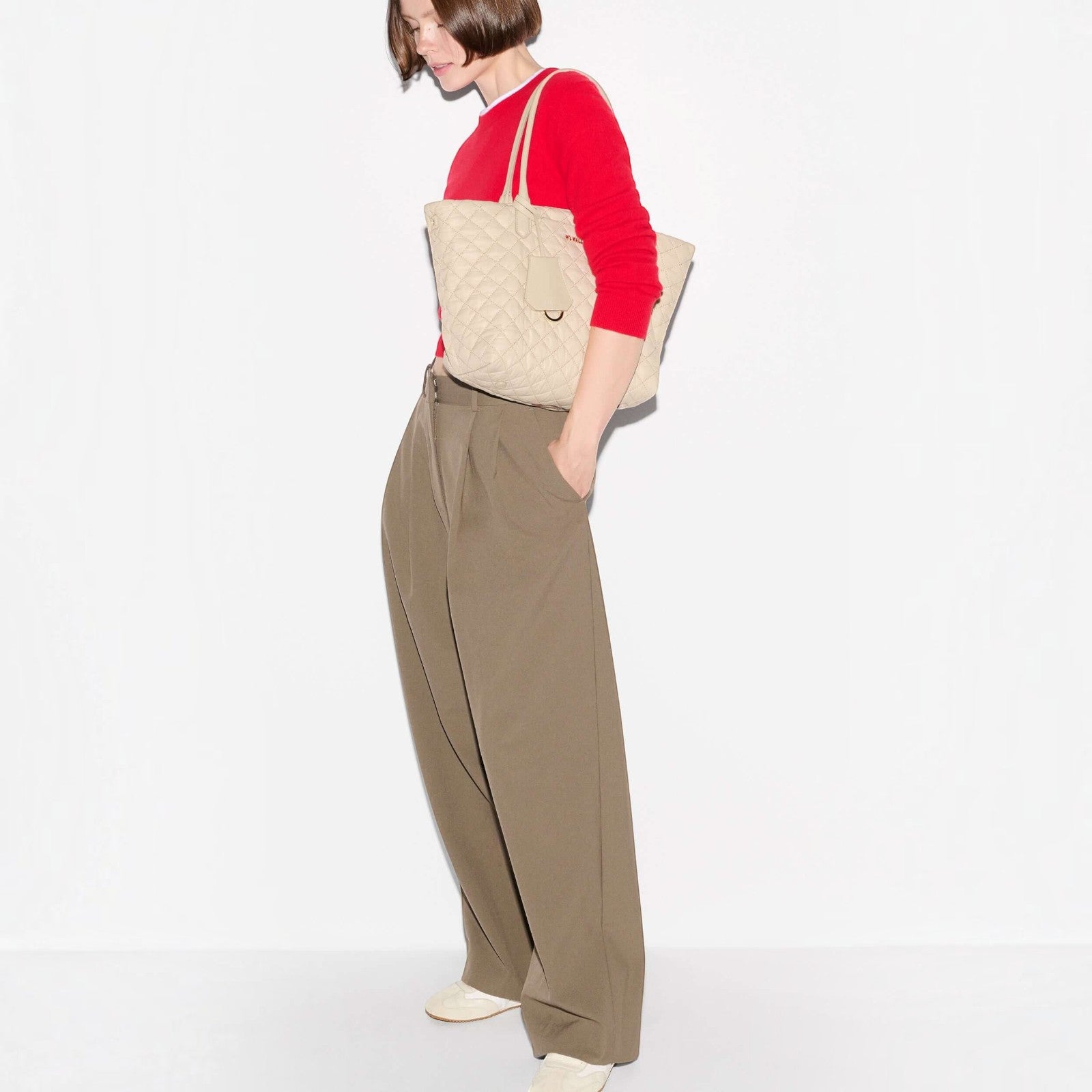 Shop Rescue Spa sand quilted nylon daily tote bag with Italian leather handles carried by a woman in a red sweater