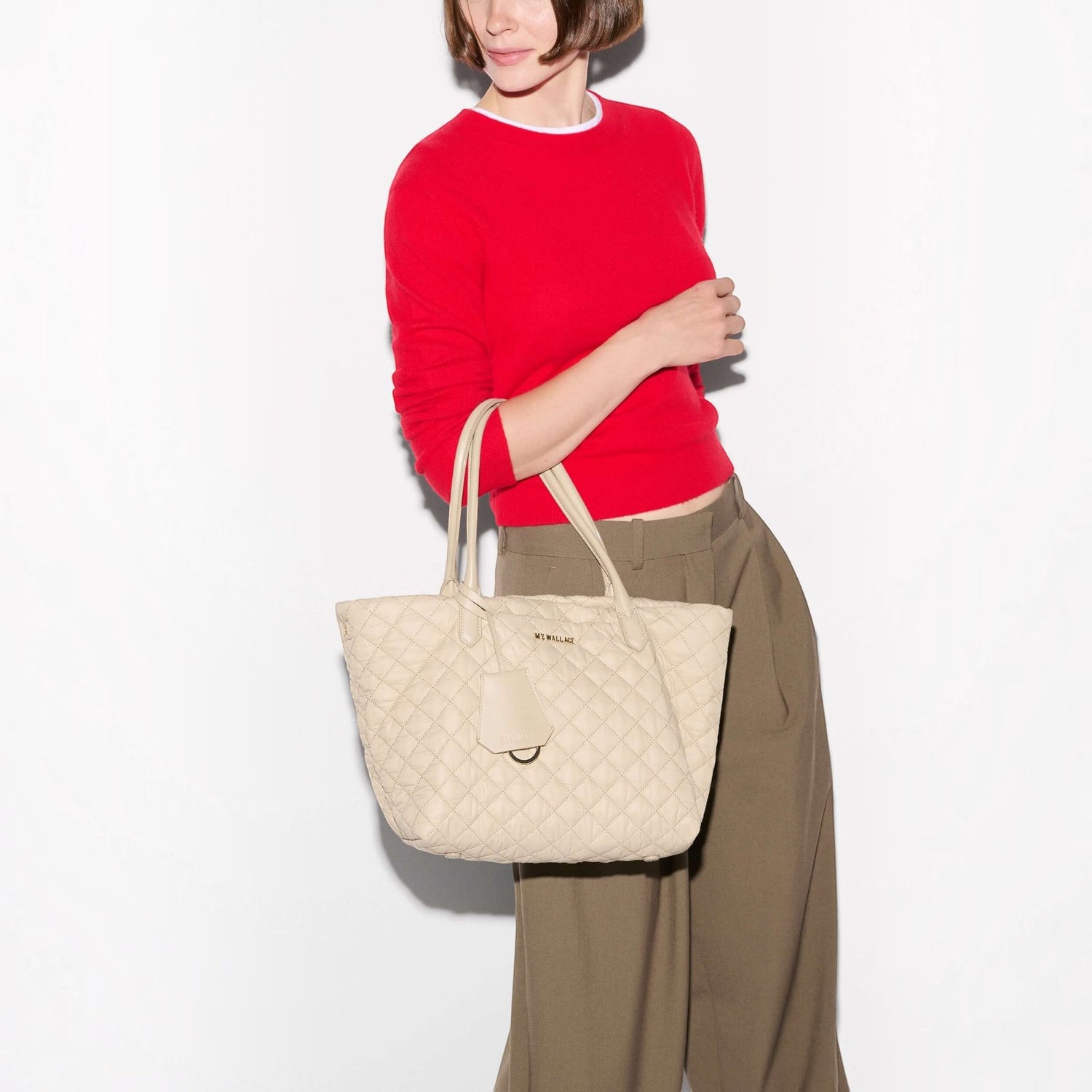 Shop Rescue Spa Sand Small Daily Tote in quilted beige nylon with Italian leather handles held by a woman