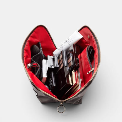 Shop Rescue Spa Signature Leather Makeup Bag with red interior, holding makeup palettes, lipstick, and cream.