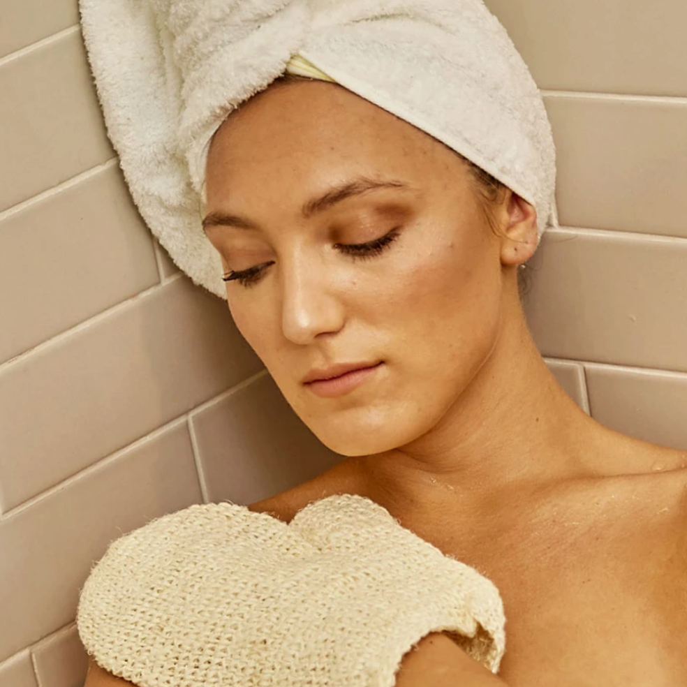 Shop Rescue Spa natural sisal bath body glove used by a woman with a towel on her head in a tiled shower
