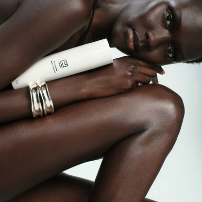 Shop Rescue Spa The Super Body Hydrator white tube held by a model with radiant skin and silver bracelets