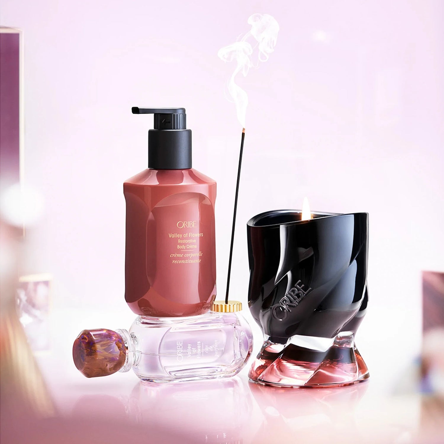 Shop Rescue Spa Oribe Valley of Flowers Eau de Parfum and Restorative Body Creme with a lit candle and incense stick.