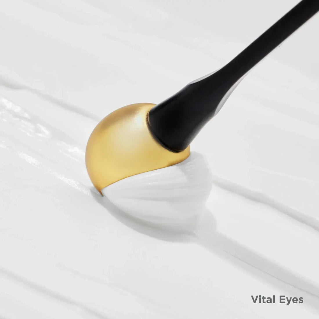 Shop Rescue Spa Isdinceutics Vital Eyes cream being applied with a gold cooling applicator on a smooth white texture.