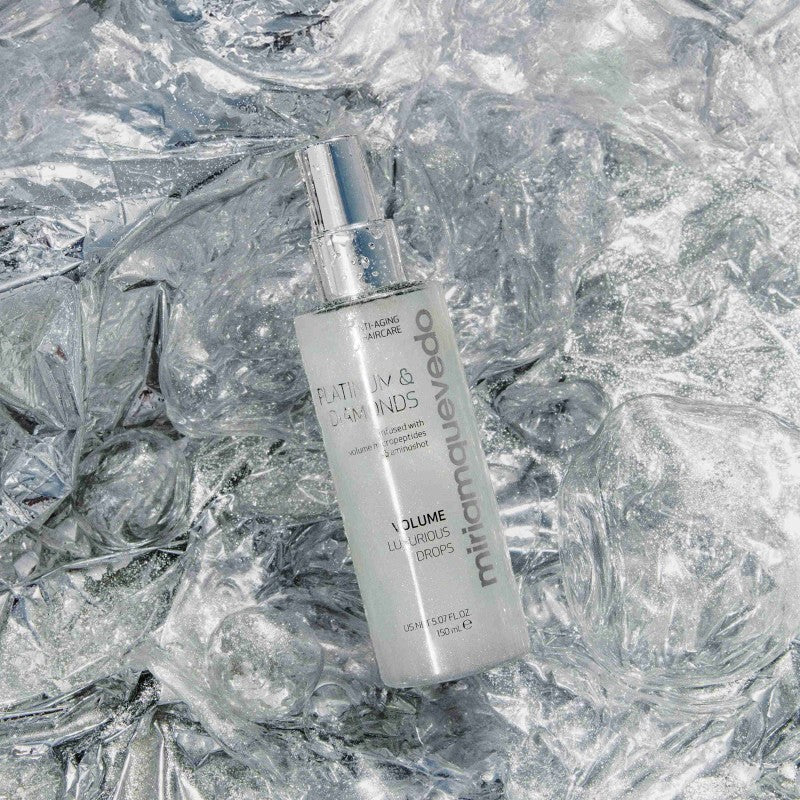 Shop Rescue Spa Volume Luxurious Drops hair mist bottle on a reflective silver crinkled background.