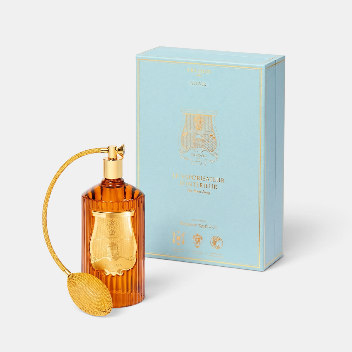 Trudon Altair room spray in an amber glass bottle with a gold atomizer bulb next to its light blue box