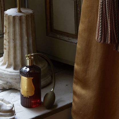 Decorative bottle with gold cap on a surface with architectural elements in the background