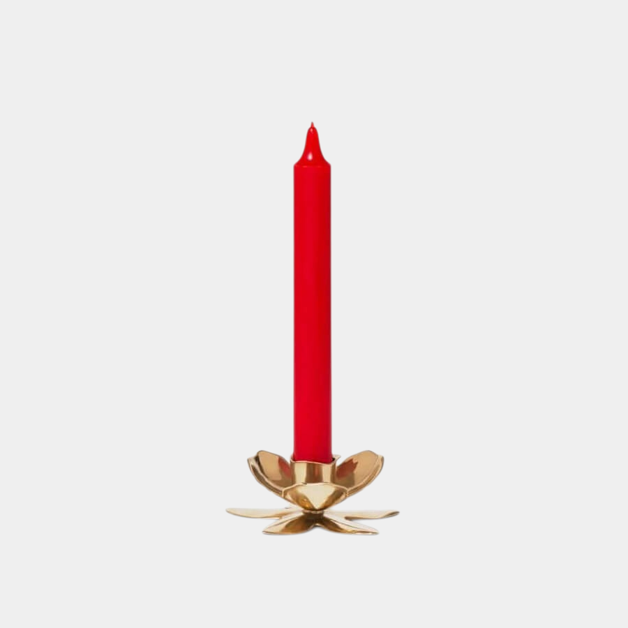 Shop Rescue Spa gold plated flower shaped candlestick holding a slim red taper candle on a plain background