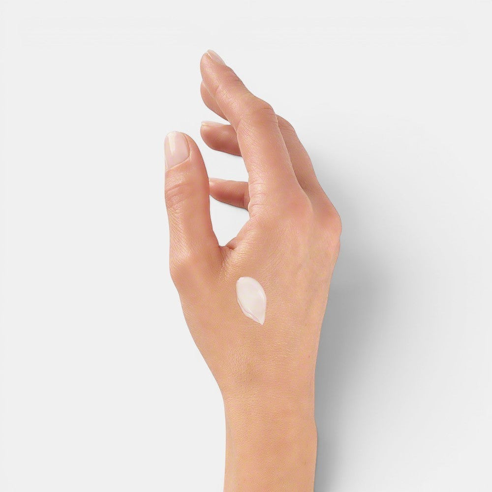 Right hand with Valmont Prime Renewing Pack cream applied near thumb area, showing texture on skin.