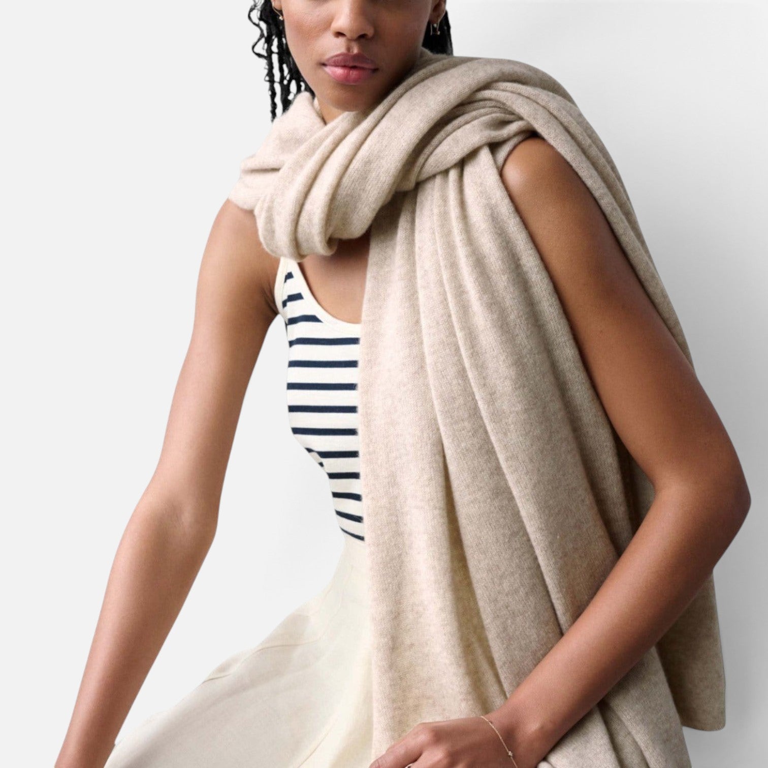 Shop Rescue Spa beige cashmere travel wrap draped over a model wearing a striped tank top